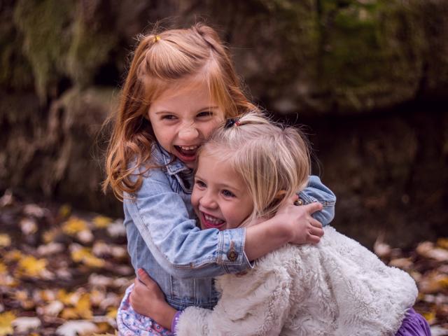 Two girls hugging in woods in autumn