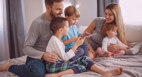 Man and woman couple with three young children on a bed