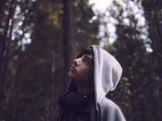 Teenage boy in the woods with hood up